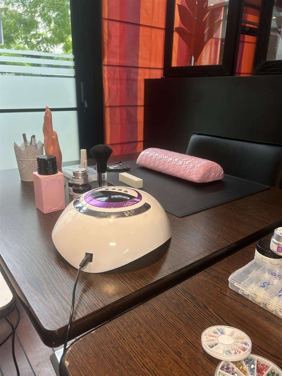 Un poste de travail équipé : lampe UV, repose-main et matériel de prothésie ongulaire